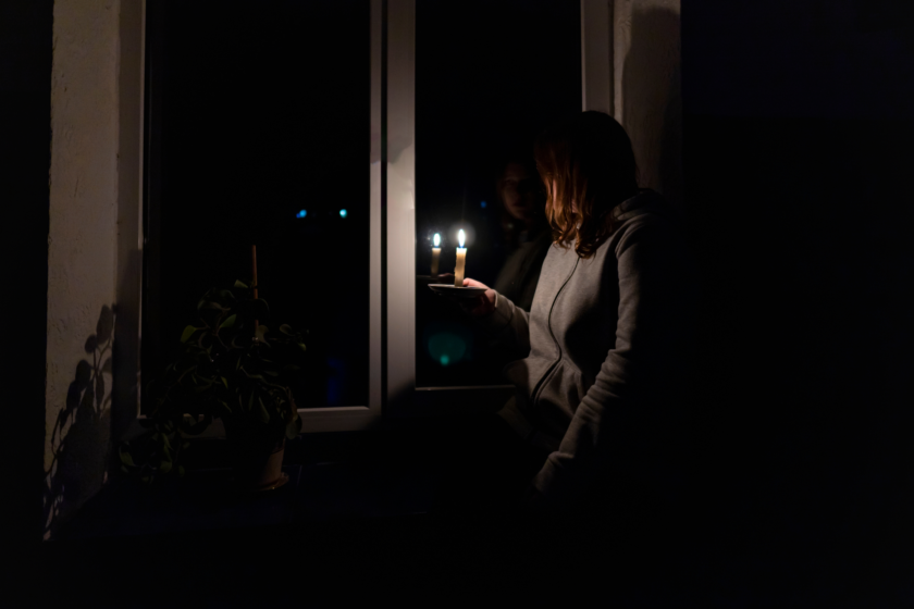 Kvinna tittar ut genom fönstret med ett ljus i handen det är mörkt ute