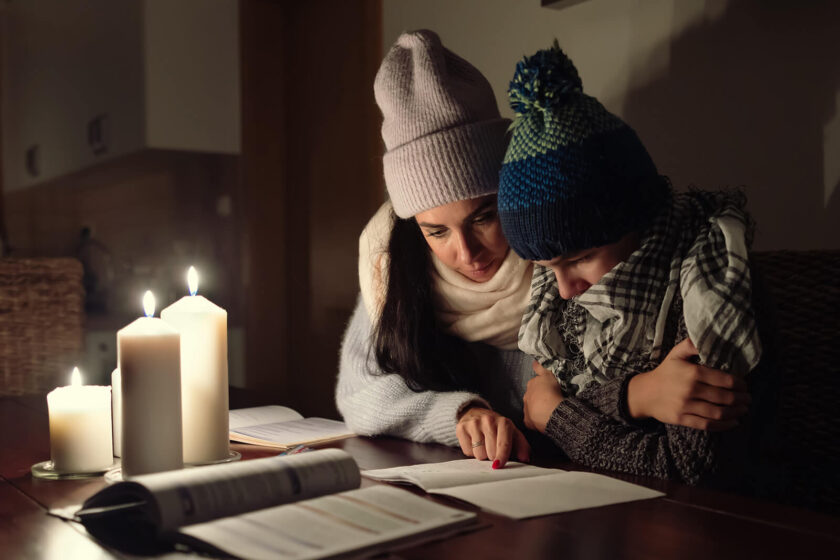 mamma och son sitter i mörkret och läser läxor med mössorna på