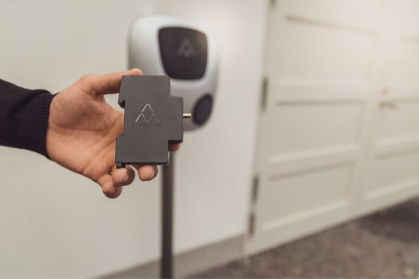 Hand som håller i Charge Amps Amp Guard lastbalanserare