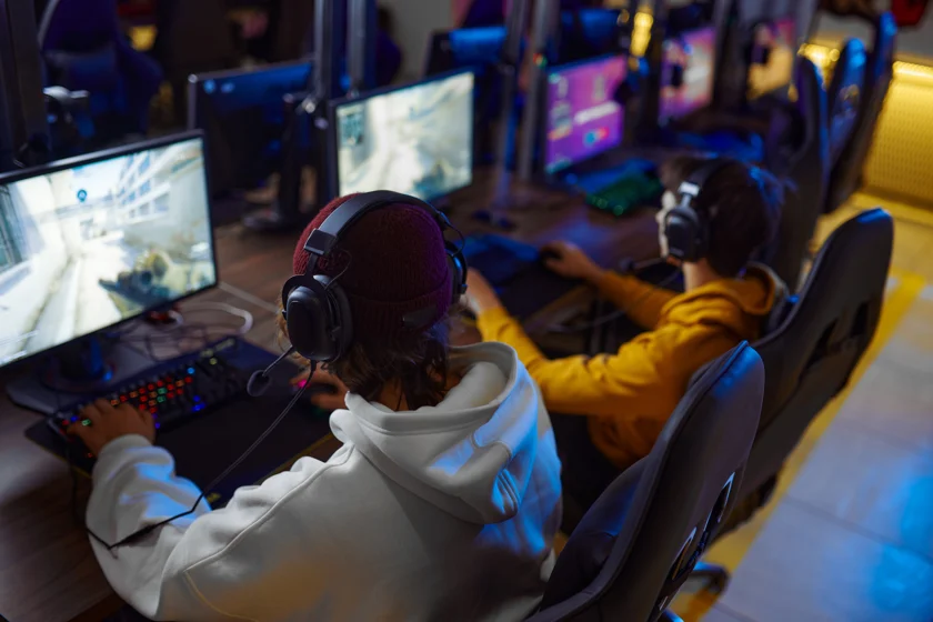 Two young gamers play in game club. Virtual entertainment, e-sport tournament, cybersport lifestyle. Male person leisures in internet cafe